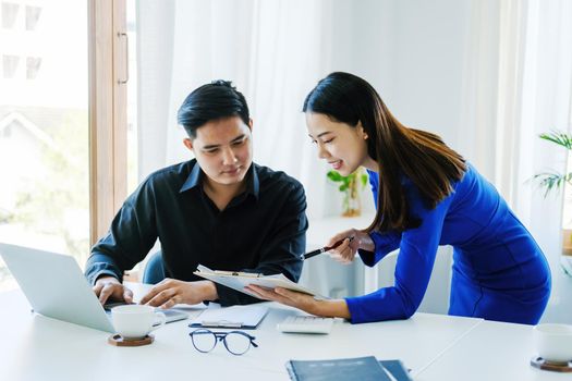 Teamwork concept, consultation, female advisor pointing to budget, finance and investment papers, discussing and planning finances with male economists in conference room