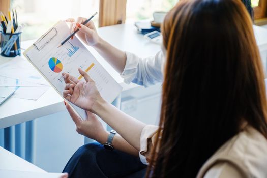 Negotiation, Analysis, Discussion: Portrait of an Asian woman economist and marketer pointing to a financial data sheet to plan investments to prevent risks and losses for the company.