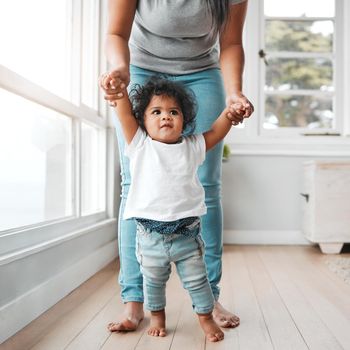 Shot of a little girl learning to walk with the help of her mother.