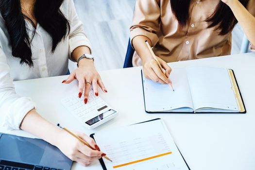 Negotiation, Analysis, Discussion, Asian woman economist and marketer pointing to a financial data sheet to plan investments to prevent risks and losses for the company.