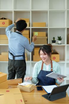 Portrait of a small start-up and SME owner, an Asian male and female entrepreneur checking orders and packing for customers, self-employed, freelance, online selling.