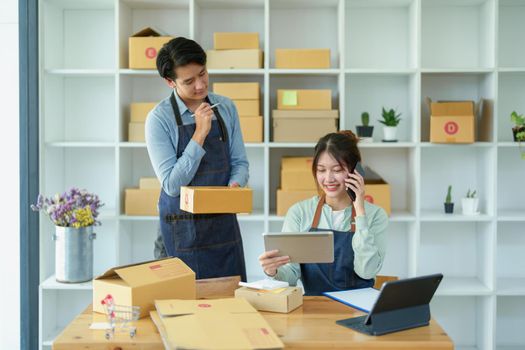 Portrait of a small start-up and SME owner, an Asian male and female entrepreneur checking orders and packing for customers, self-employed, freelance, online selling.