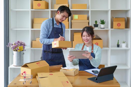 Portrait of a small start-up and SME owner, an Asian male and female entrepreneur checking orders and packing for customers, self-employed, freelance, online selling.