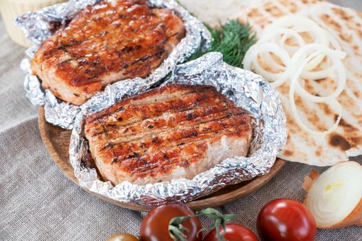 Grilled pork meat in foil with flapjack and vegetables. Summer rest concept