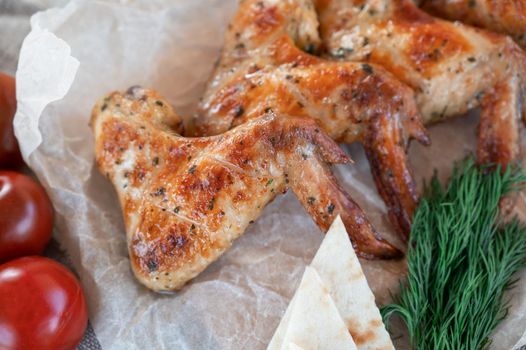 Ready spicy grilled chicken wings with greens and tomato. Summer rest concept