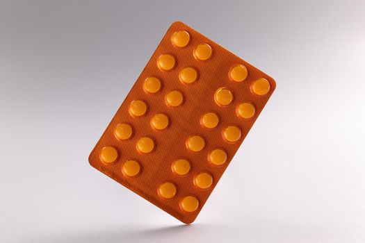 Close-up of blister with tablets, daily dose of medication for person. White tablets in orange package. Prescription, recovery, medicine, health concept
