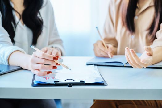 Negotiation, Analysis, Discussion, Asian woman economist and marketer pointing to a financial data sheet to plan investments to prevent risks and losses for the company.