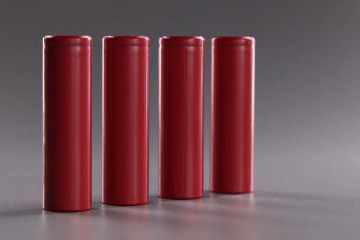 Close-up of set of four rechargeable batteries, lithium battery, important power source. Battery mods with electrical energy on grey surface. Power concept