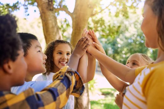 Shot of a group of kids giving each other a high five at summer camp.