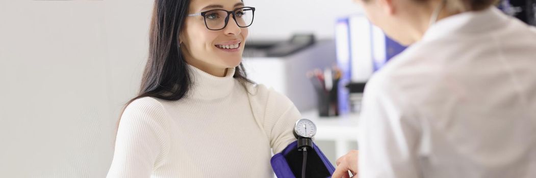 Portrait of doctor measuring patients blood pressure with tonometer tool and talk. Planned checkup at family doctor. Medicine, healthcare, clinic concept