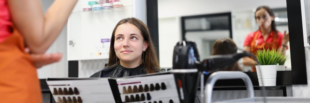 Portrait of pretty woman client hold palette of colours for hair dye at hairdresser appointment. Beauty treat at professional master. Image change concept