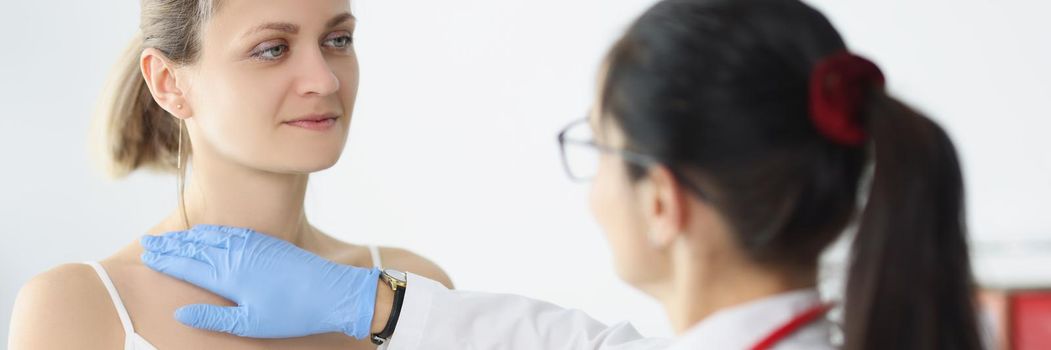 Portrait of blonde female on doctors appointment being examined by professional medical worker. Nurse touch neck and chest. Provide help, health concept