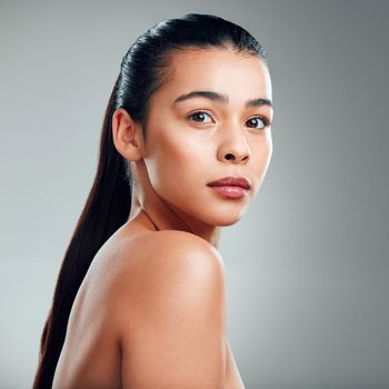 Studio shot of a beautiful young woman posing against a grey background.