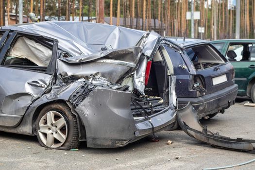 Broken car after a traffic accident in the parking lot of a repair station. Car body damage workshop outdoors. Sale of insurance cars. Accident on the street, car after a collision in the city