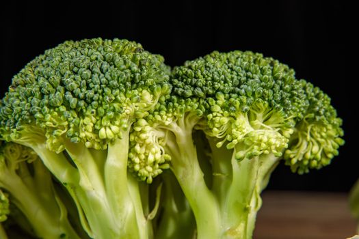 Raw green broccoli florets on a wooden board with ingredients. Close-up.