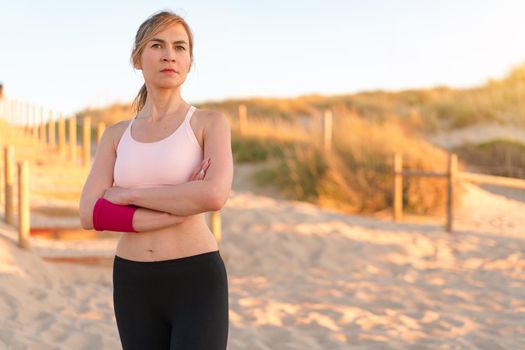 Athletic woman portrait outdoor. Caucasian female sportive woman standing on nature ocean beach. Confident middle age fit woman summer day