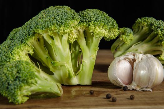 Raw green broccoli florets on a wooden board with ingredients. Close-up.