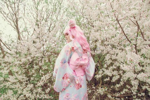 Portrait of young european woman wearing kimono. Asian beauty. Cherry blossoms. Hanami. Sightseeing of Japan concept.