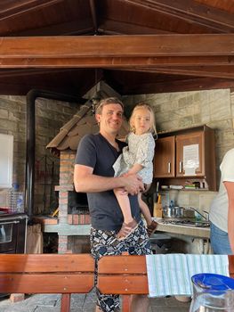 Dad holding a little girl in his arms indoors with a fireplace. High quality photo