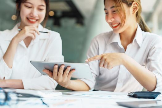 Negotiation, Analysis, Discussion, Portrait of an Asian women economist and marketer using tablet computer to plan investments and financial to prevent risks and losses for the company.