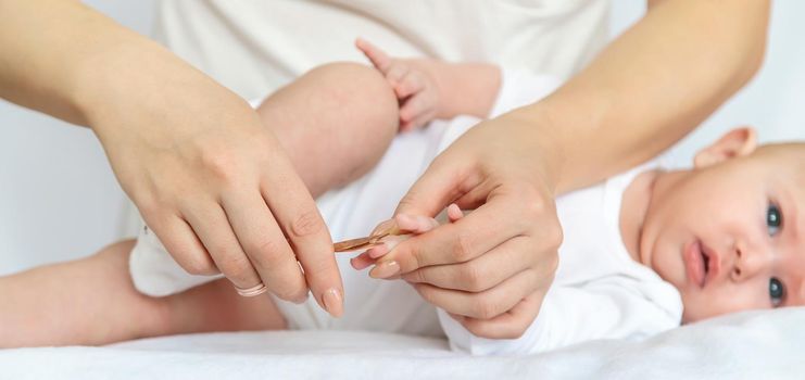 Mother cuts baby's fingernails on light background. Selective focus. people.