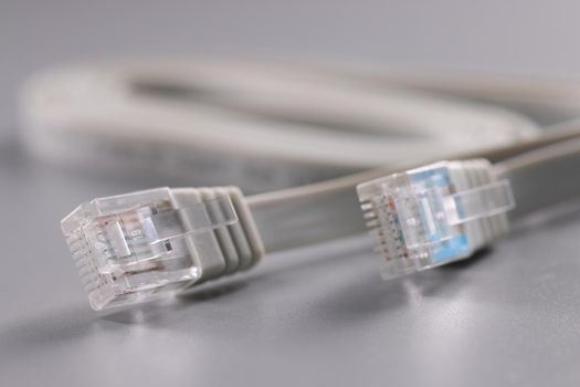 Close-up of pair of internet connectors on grey background, cable with plastic clip. Internet and telecommunications, modern technology, service concept