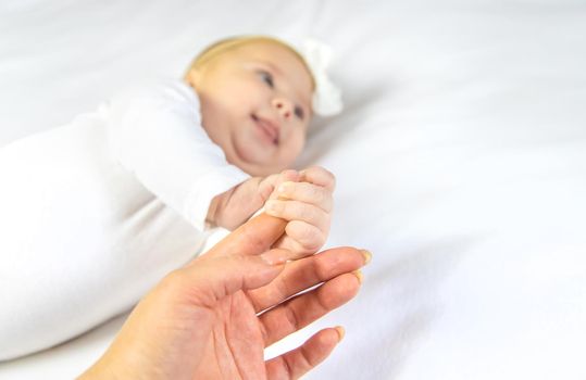 Baby hands with mom's hands against white background. Selective focus. People.