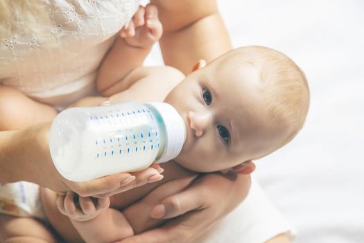 Mom feeds the baby with a bottle. Selective focus. People.