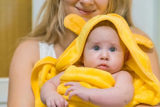 Baby after bathing in a towel. Selective focus. People.