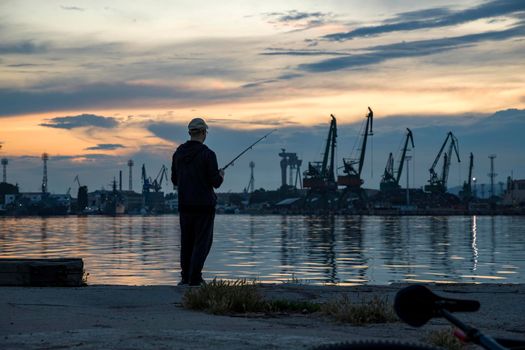 Silhouette of fisherman in the harbor at amazing sunset