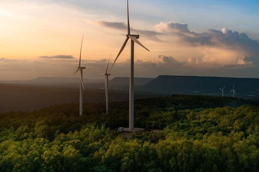 Wind energy. Wind power. Sustainable, renewable energy. Wind turbines generate electricity. Windmill farm on a mountain with sunset sky. Green technology. Renewable resource. Sustainable development.