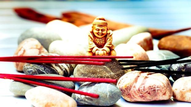 Think deeply or focus ones mind for a period of time, in silence, for religious or spiritual purposes or as a method of relaxation.Statuette of a Buddhist monk among incense and various stones