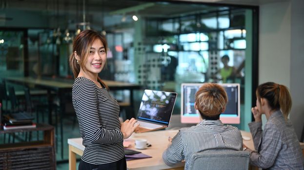 Software engineers team leader standing with laptop and smiling to camera. Developing programming and coding technologies concept.