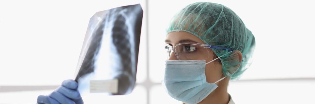Portrait of qualified female doctor examine x ray scan of patients lungs. Medical worker prescribe full diagnostic and analysis. Covid, disease concept