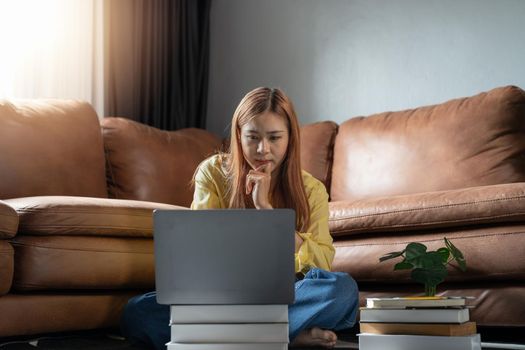 Thoughtful serious indian woman working on laptop thinking solving problem, online education at home