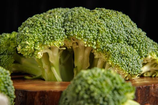 Raw green broccoli florets on a wooden board with ingredients. Close-up.