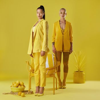Shot of two women dressed in stylish yellow clothes against a yellow background.
