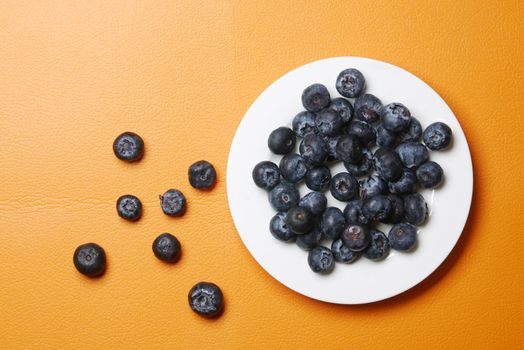top view of fresh blue berry on orange background .