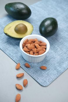close up of slice of avocado and almond nut on chopping board.,