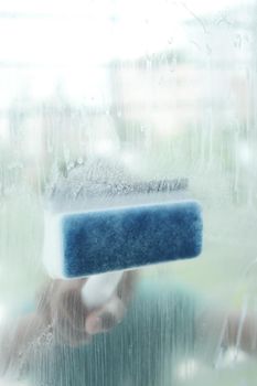 Close up of man hand cleaning window glass .