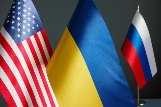 Near flags of the USA and Ukraine and the flag of Russia.