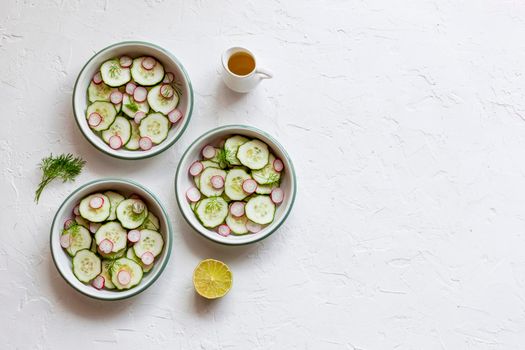 radish and cucumber salad served in a three small round bowls, top view, copy space