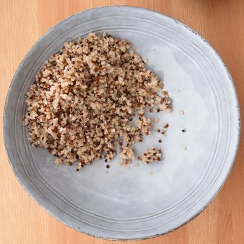 Blue bowl with quinoa on wooden surface, image 2 of 8