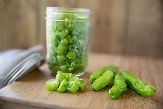 Fresh shishito peppers, whole, siced, and in canning jar ready to be pickled.