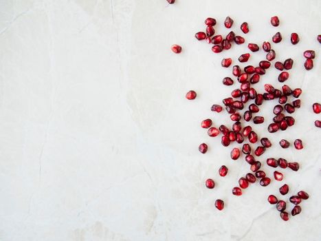 Flat lay pomegranate seeds on marble surface with copy space.