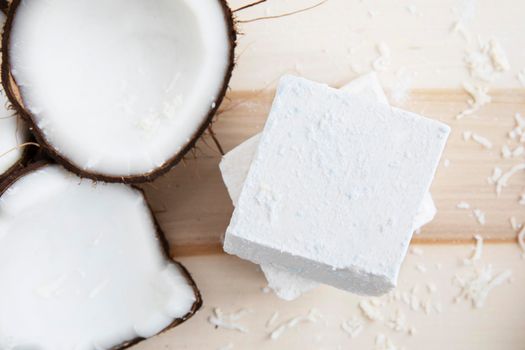 Coconut pieces and two bars of coconut soap with a top down view.