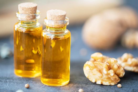 Two small bottles of walnut oil and walnuts close up.