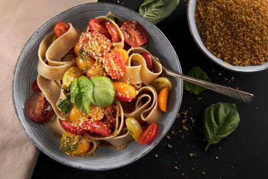 Healthy whole wheat pappardelle pasta with fresh tomatoes and basil, and a vegan nut based topping.
