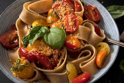 Healthy whole wheat pappardelle pasta with fresh tomatoes and basil, and a vegan nut based topping.