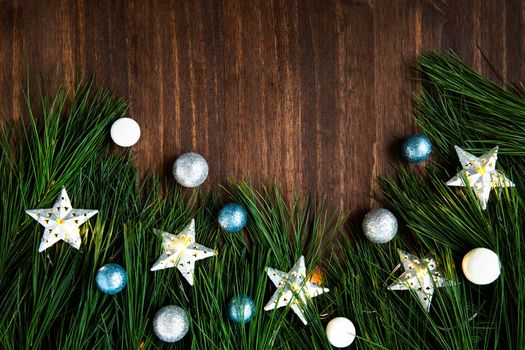 Pine boughs with christmas decorations on wooden surface with copy space.